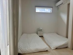 two beds in a white room with a window at 嘉翔の家 in Otsu