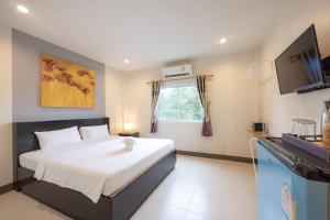 una camera da letto con un letto grande e una televisione di Baan Yuyen Karon Guesthouse a Karon Beach
