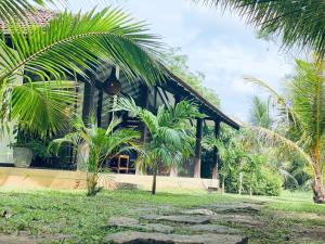 a house with palm trees in front of it at Neem Jay Beach Resort in Tangalle