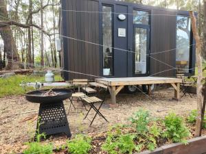 una piccola casa nel bosco con un tavolo e una griglia di Solitary Islands Farm 3 by Tiny Away ad Arrawarra