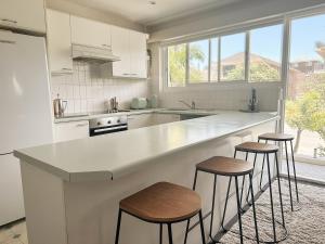 a kitchen with a white counter and stools in it at 150m to Dee Why Beach in Deewhy