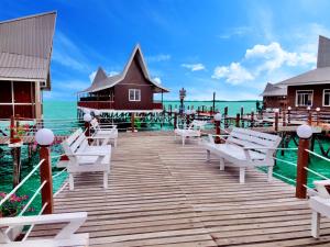 Starz Water Village仙本那星星美亚水屋 في سيمبورنا: رصيف خشبي مع كراسي بيضاء على الماء