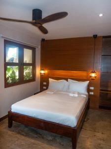 a bedroom with a bed with a ceiling fan at Kāpena Siargao in General Luna