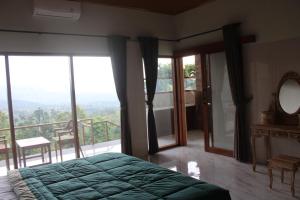 een slaapkamer met een bed en een balkon met ramen bij Rumah Bagus Jayanti in Sidemen +15 foto's