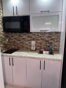 een witte keuken met een spoelbak en een magnetron bij Isla Verde Beach Dreamscape in San Juan