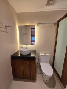 a bathroom with a white toilet and a sink at Kāpena Siargao in General Luna