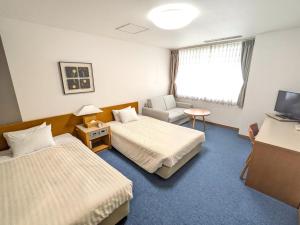 um quarto de hotel com duas camas e uma televisão em Hotel Shinanoji em Nagano