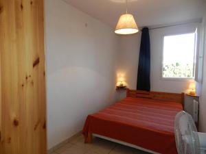 Un dormitorio con una cama roja con una ventana. en Appartement 3 pièces avec loggia, proche mer, 6 couchages - Bormes-les-Mimosas - FR-1-251-897, en La Favière