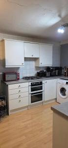 a kitchen with white cabinets and a stove top oven at Private Room in Amley