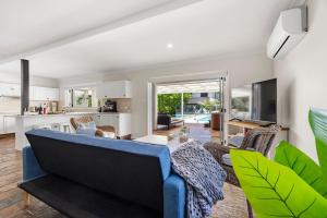 a living room with a blue couch and chairs at 35 South - Pet Friendly Beach House with Pool, Spa in Vincentia