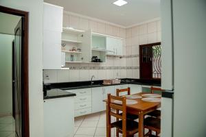 Una cocina con gabinetes blancos y una mesa de madera. en Ev Home, en Cruzeiro do Sul