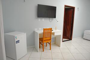 Un escritorio con una silla y un televisor en una pared. en Ev Home, en Cruzeiro do Sul
