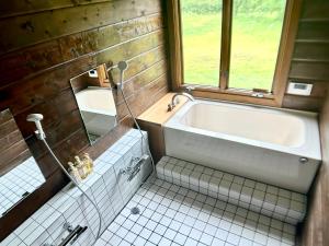 a bathroom with a bath tub and a window at 実と來-mitoki in Takayama