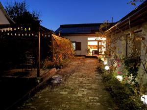a brick pathway leading to a house at night at Lisbet Cottage in Kecskemét