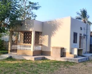 una piccola casa bianca con una panchina nel cortile di Swahili beach home a Mombasa