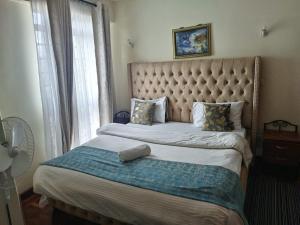 una camera con letto con testiera trapuntata e finestra di Swahili beach home a Mombasa