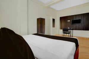 a bedroom with a bed and a chair and a television at Super Hotel O Symbiosis University Nagpur Formerly Royal Villa Inn in Sakardarā