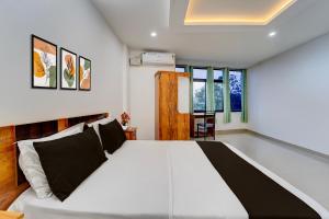 ErumeliHotel O Erumeli Bus Terminal Kottayam Formerly Pious B Residency的卧室里有一张白色的大床，配有黑色的枕头