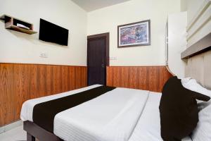 科塔Collection O Jhalwar Road的一间卧室，墙上有一张床和一台电视