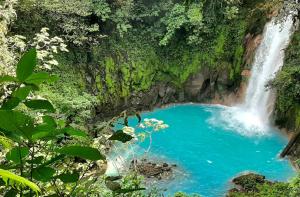 una cascada en medio de una piscina azul de agua en Reserva Atmosfëre, en Upala