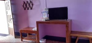 a desk with a monitor and a bench in a room at Saran Resort room 13 in Ban Khok Wat