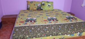 a bed with a bedspread with cartoon bugs on it at Saran Resort room 13 in Ban Khok Wat