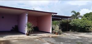 a pink house with palm trees in front of it at Saran Resort room 13 in Ban Khok Wat