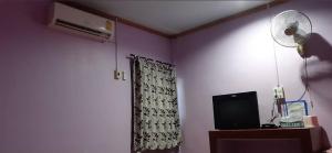 a room with a purple wall with a fan and a television at Saran Resort room 13 in Ban Khok Wat