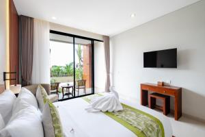 una habitación de hotel con una cama y un televisor en Three Brothers Munggu Suites Villas and Restaurant, en Pererenan