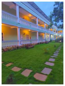 a large building with a green yard with benches at Le French Nest in Puducherry