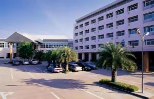 um parque de estacionamento com palmeiras em frente a um edifício em Western Grand Hotel Ratchaburi em Ratchaburi