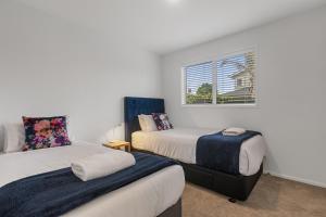 ein Schlafzimmer mit zwei Betten und einem Fenster in der Unterkunft Endless Summer Retreat - Mt Maunganui in Mount Maunganui