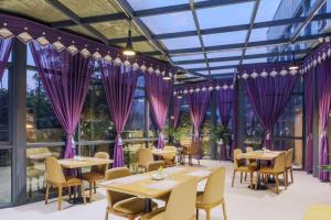 un restaurante con cortinas moradas, mesas y sillas en Nanning Champs Elysees Hotel, en Nanning