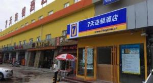 un edificio giallo con un ombrello rosso davanti di 7 Days Inn Beijing Shunyi Development Area Mordern Motor City a Tahe