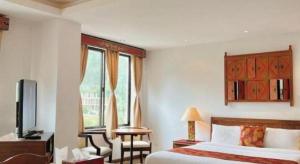 a hotel room with a bed and a tv and a window at Khang Residency Thimphu in Thimphu