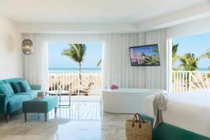 Un dormitorio con una cama y una bañera y una playa. en EXCELLENCE PUNTA CANA - ALL INCLUSIVE - ADULTS ONLY, en Punta Cana
