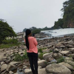 a woman standing on rocks taking a picture of the water at 1052grovest in Irvington