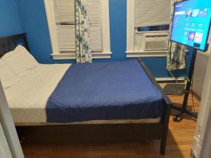 a bedroom with a bed with a blue wall and windows at 1052grovest in Irvington