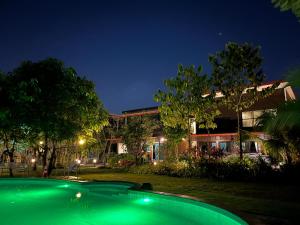 a house with a swimming pool at night at BaanSuanklaiKlungBangkrachao บ้านสวนใกล้กรุงบางกะเจ้า in Phra Pradaeng