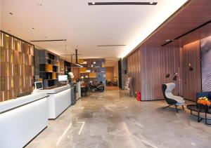 a large lobby with a desk and a chair at Echarm Hotel Jinan West Station International Exhibition Center in Jinan