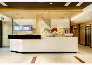 Dos mujeres sentadas en un mostrador en un vestíbulo. en Borrman Hotel Tai'an Central Hospital Taishan Tianwai Village Hongmen, en Tai'an