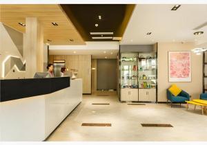 Un hombre sentado en un mostrador en un vestíbulo. en Borrman Hotel Tai'an Central Hospital Taishan Tianwai Village Hongmen, en Tai'an