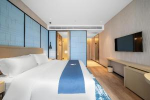 a bedroom with a large white bed and a flat screen tv at Echarm Hotel Jinan West Station International Exhibition Center in Jinan +211 photos