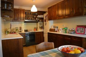 una cocina con armarios de madera y un bol de fruta en una mesa en Vasiliki's House en Mitilene