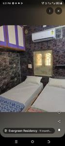 two beds in a room with a wall with a window at Evergreen Homestay in Dwarka