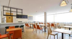 a dining room with tables and chairs and a kitchen at City Comfort Inn Lijiang Ancient Town in Lijiang