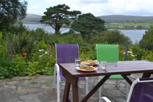 Dunmanus Cottage West Cork في Durrus: طاولة خشبية مع صحن طعام وكرسيين