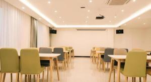 济南GEM Hotel Zibo Economic Development Zone Zibo Vocational Institute的一间配有桌椅和白板的会议室