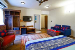 a living room with a bed and chairs and a tv at Open Hotel by Olive - Utse Suites in Bengaluru +12 photos