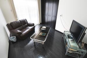 a living room with a leather couch and a tv at 外宮前別邸　星凪庵 in Ise
